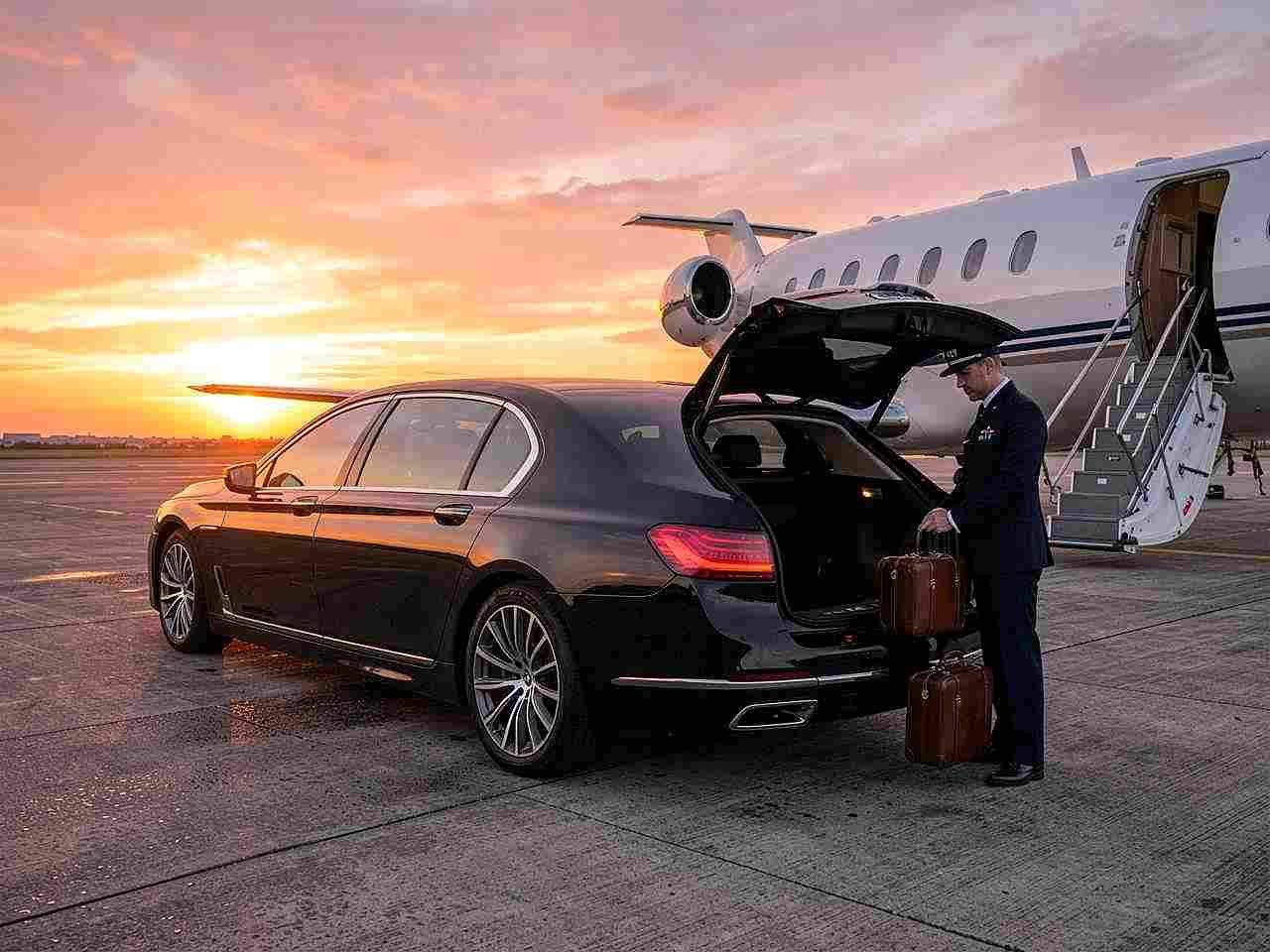 Black BMW 7 Series with professional chauffeur assisting passenger with luggage at the Dubai airport