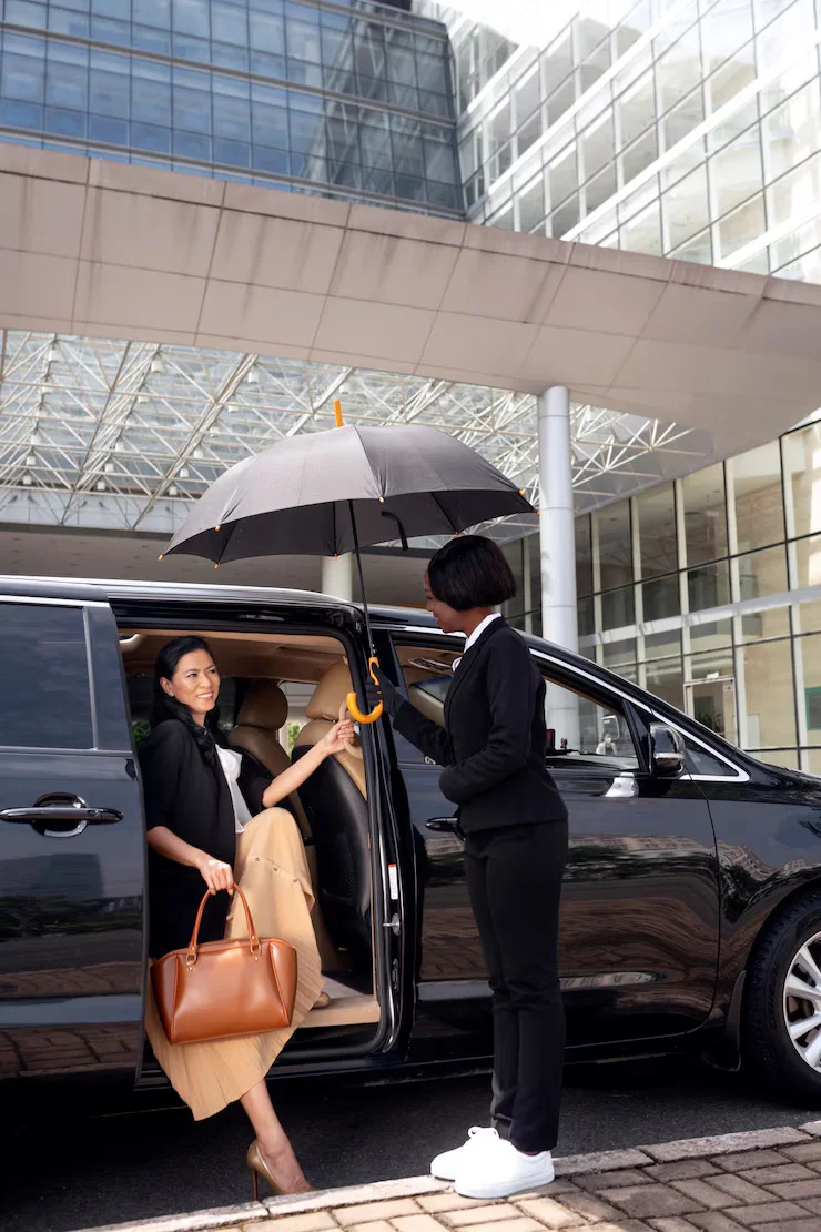 Woman getting out of a black Mercedes V-Class with a chauffeur holding an umbrella in Dubai